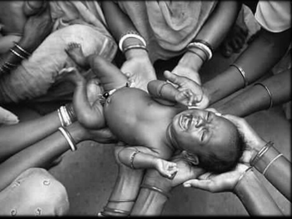 An infant supported in a circle of hands