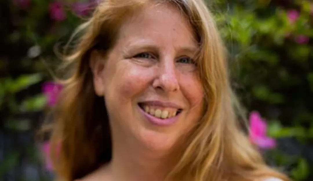 Laura Oldanie wearing a white shirt in front of flowers bushes with red blossoms. Text on the image reads Permaculture Values and Impact Investing Laura Oldanie